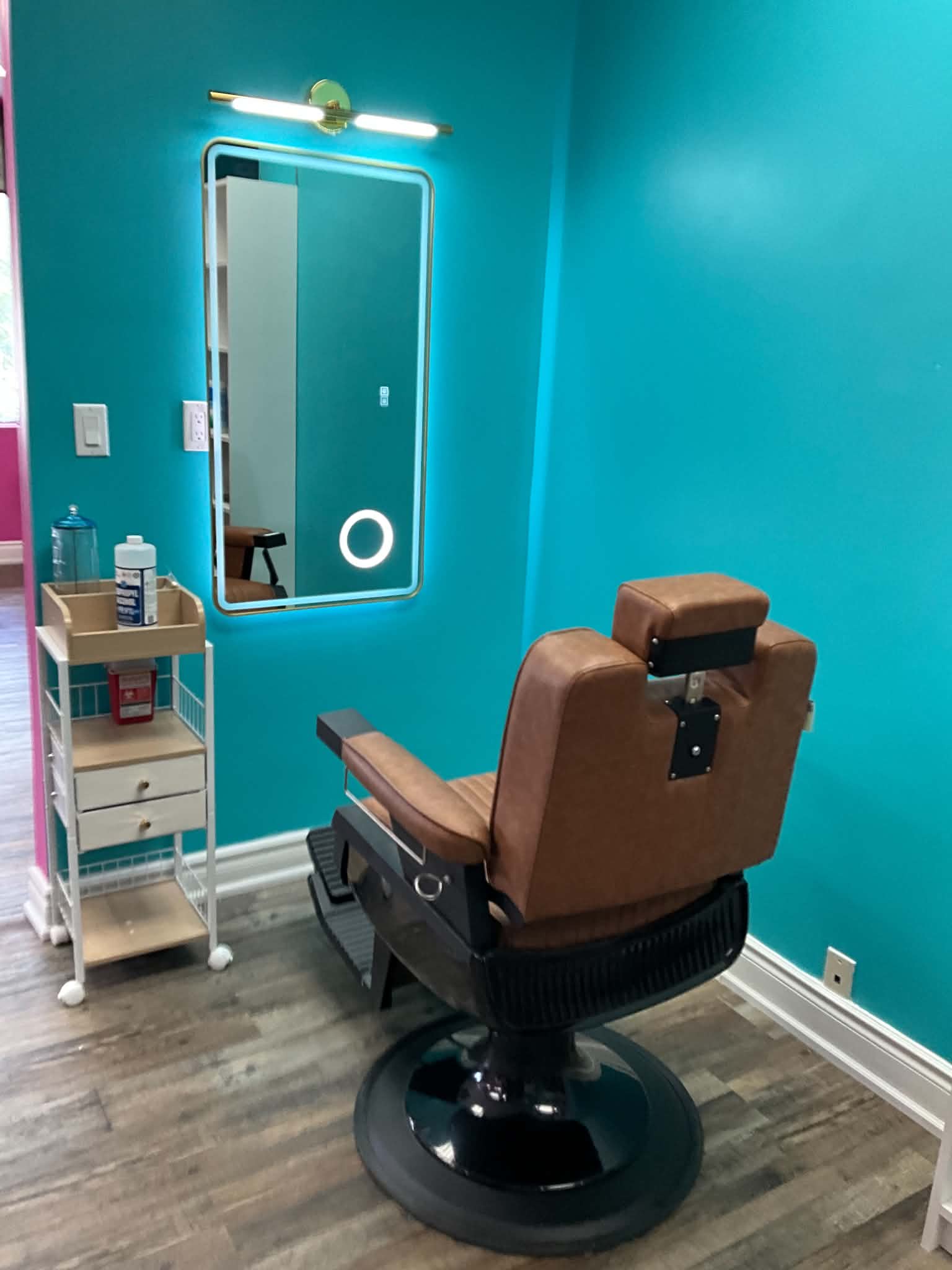 Dedicated styling station with backlit mirror against a teal wall